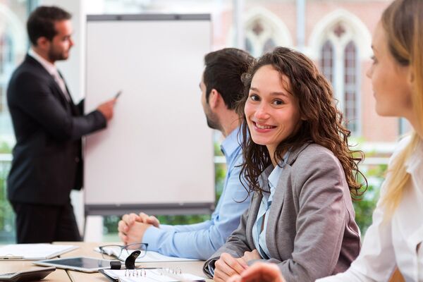Junge Frau sitzt mit anderen Schülern am Tisch