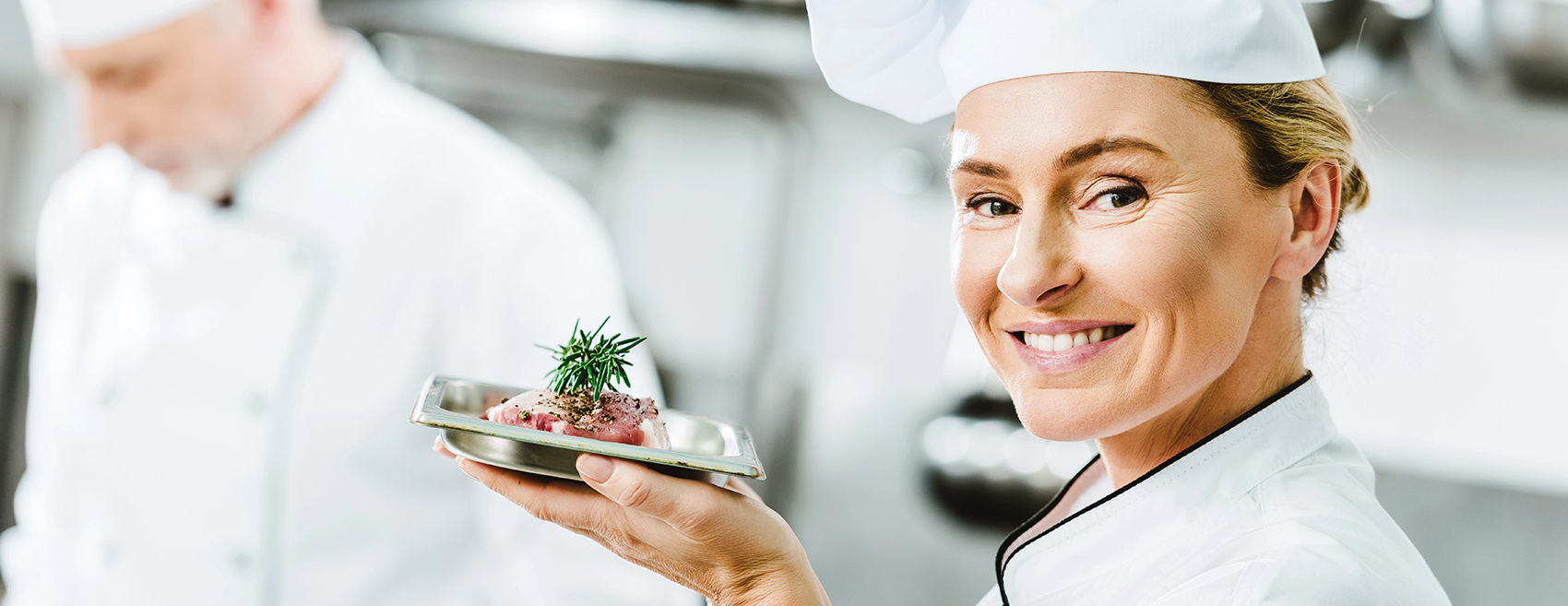 Eine junge Köchin präsentiert einen Teller mit Essen